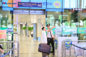 Nhân viên an ninh sân bay Tân Sơn Nhất hướng dẫn hành khách đi lại.